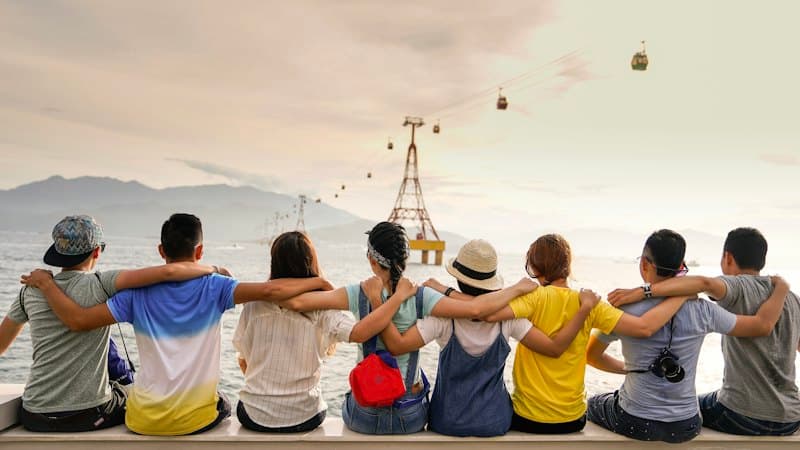 A group of friends sitting together, looking out at a cable car over the hills